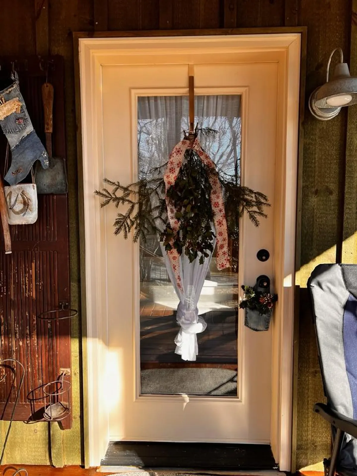 A warmly decorated exterior front door featuring a festive wreath, textured wall, and inviting details that signal a welcoming atmosphere. The image conveys the sense of arriving at a charming mountain retreat, with hints of the natural and cozy setting surrounding the home.